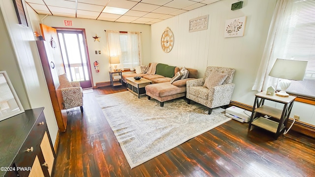 living room with a paneled ceiling and dark hardwood / wood-style floors