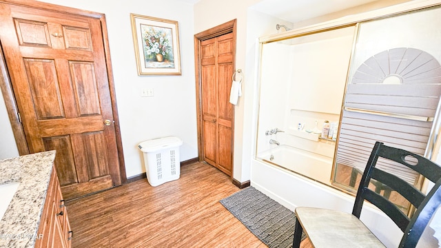 bathroom with hardwood / wood-style floors, vanity, and enclosed tub / shower combo