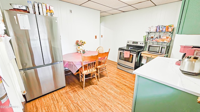 kitchen featuring a drop ceiling, stainless steel appliances, green cabinetry, and light wood-type flooring