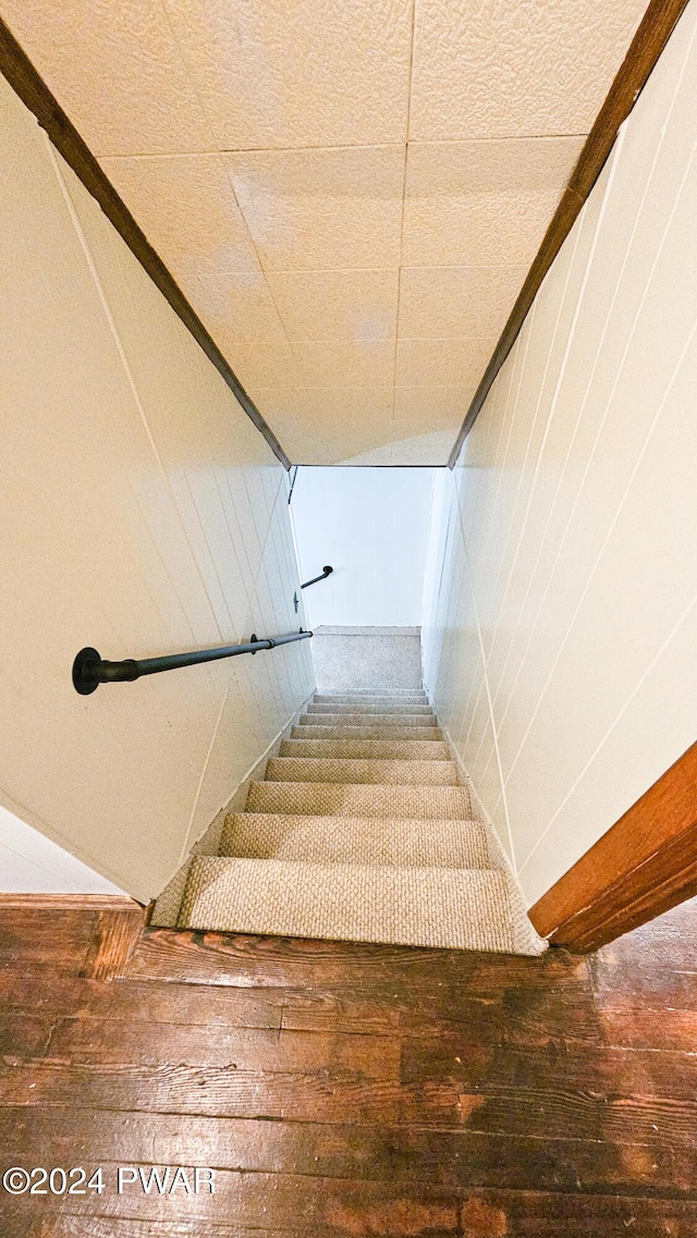 stairway featuring wood walls and wood-type flooring