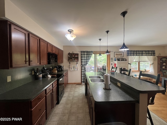 111 Bluestone Dr, Lords Valley, PA 18428 - kitchen with black appliances, dark countertops, a kitchen island with sink, and healthy amount of natural light