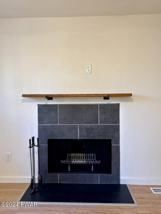 room details featuring wood-type flooring and a tiled fireplace