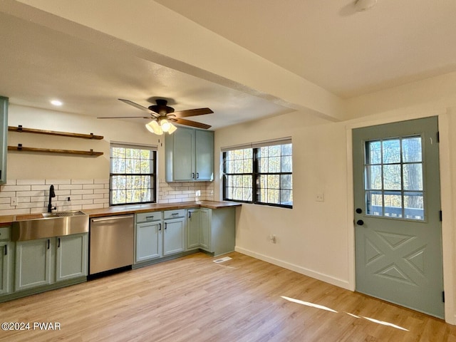 kitchen with wooden counters, tasteful backsplash, stainless steel dishwasher, sink, and light hardwood / wood-style floors