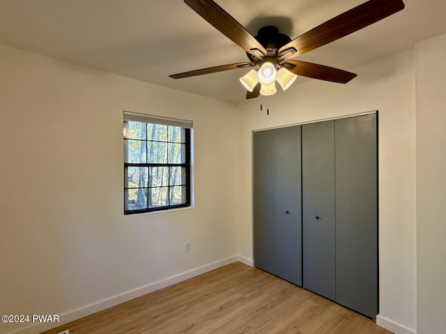 unfurnished bedroom featuring ceiling fan, light hardwood / wood-style floors, and a closet