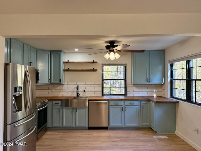 kitchen with wood counters, sink, stainless steel appliances, and tasteful backsplash