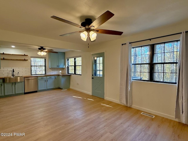 kitchen featuring light wood-type flooring, backsplash, sink, dishwasher, and plenty of natural light