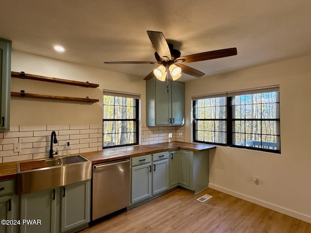 kitchen featuring a wealth of natural light, sink, tasteful backsplash, stainless steel dishwasher, and butcher block countertops