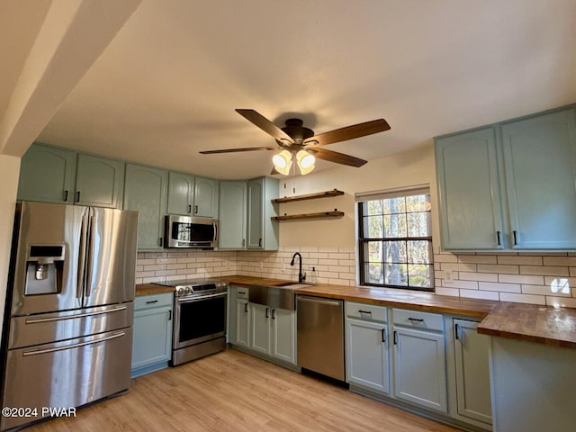 kitchen featuring wooden counters, decorative backsplash, and stainless steel appliances