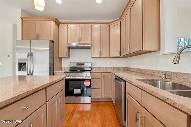 kitchen featuring appliances with stainless steel finishes, light brown cabinetry, sink, and light stone countertops