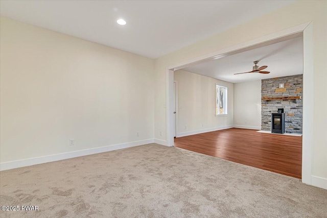 unfurnished living room featuring ceiling fan, a fireplace, and carpet