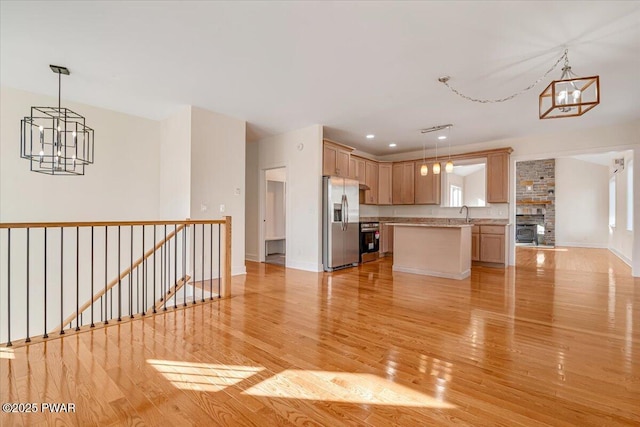 kitchen with stainless steel refrigerator with ice dispenser, light wood-type flooring, light brown cabinetry, and decorative light fixtures