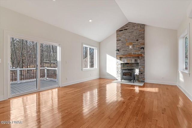 unfurnished living room with lofted ceiling, light hardwood / wood-style flooring, and a wood stove