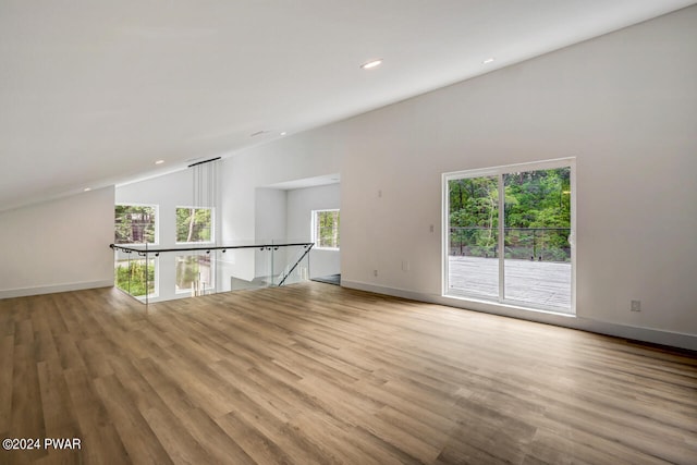 unfurnished room with a wealth of natural light, lofted ceiling, and light wood-type flooring