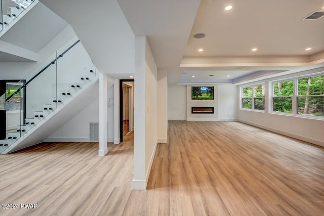 unfurnished living room featuring light hardwood / wood-style floors and a tray ceiling