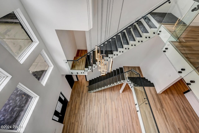 stairs with hardwood / wood-style flooring and a towering ceiling