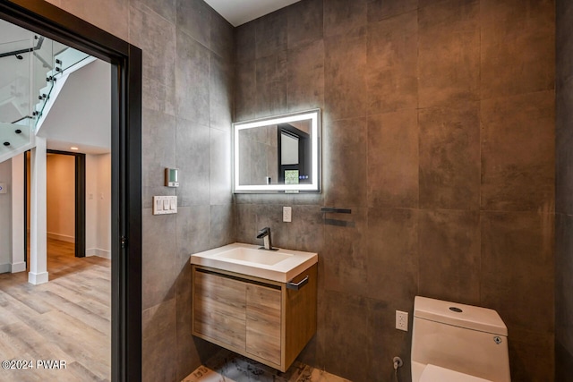 bathroom with hardwood / wood-style flooring, vanity, tile walls, and toilet