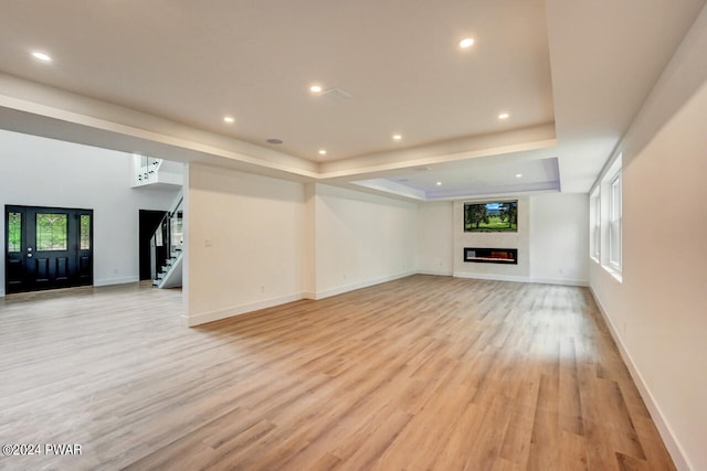 unfurnished living room featuring light hardwood / wood-style floors and a raised ceiling