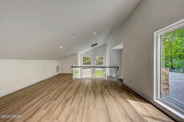 additional living space featuring light wood-type flooring and vaulted ceiling