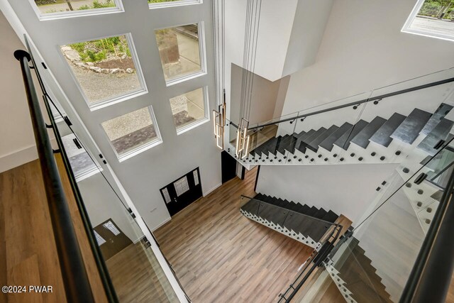 stairs with hardwood / wood-style floors and a high ceiling