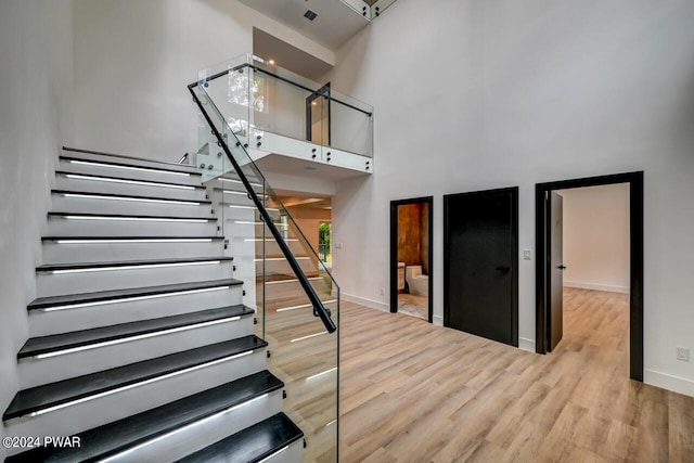 staircase with wood-type flooring, a high ceiling, and a chandelier