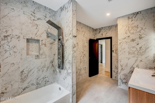 bathroom featuring tile patterned flooring, vanity, tile walls, and  shower combination