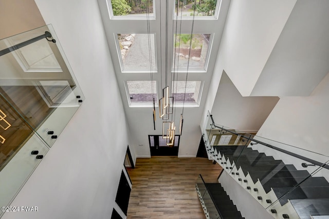 stairs with hardwood / wood-style floors and a towering ceiling