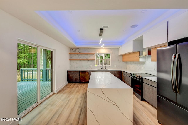 kitchen featuring light stone countertops, backsplash, black appliances, white cabinets, and a kitchen island