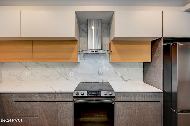 kitchen with white cabinetry, wall chimney exhaust hood, stainless steel appliances, light stone counters, and backsplash