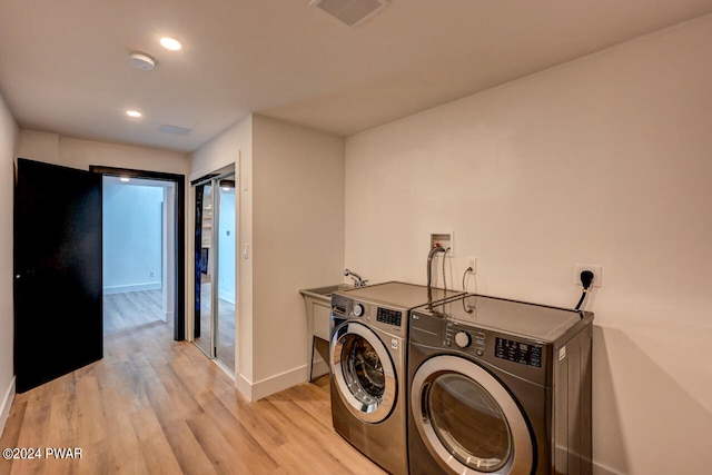 washroom featuring washing machine and dryer and light hardwood / wood-style floors