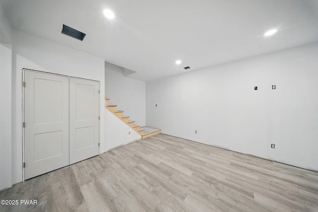 finished below grade area featuring stairs, recessed lighting, and wood finished floors