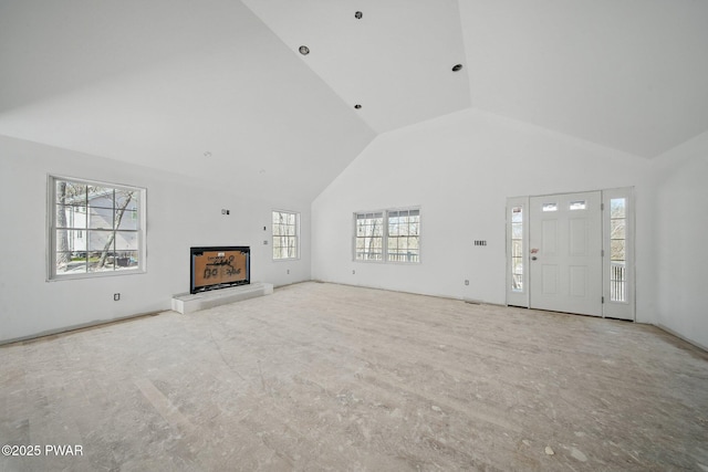 unfurnished living room featuring a fireplace with raised hearth and high vaulted ceiling