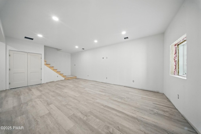 below grade area featuring recessed lighting, stairs, wood finished floors, and visible vents