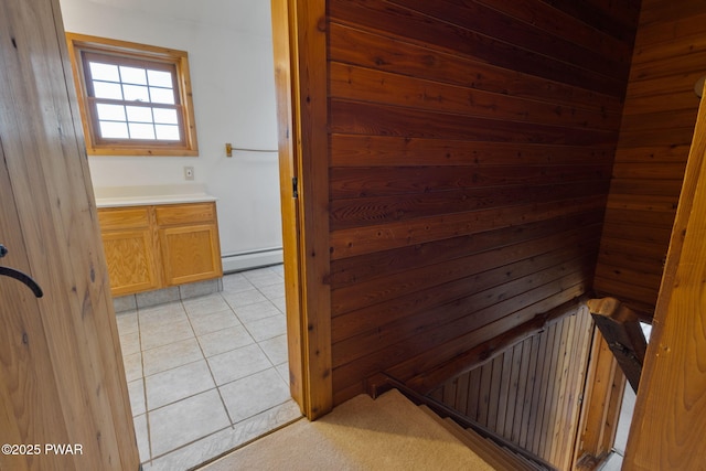 interior space with wood walls, light tile patterned floors, and a baseboard heating unit