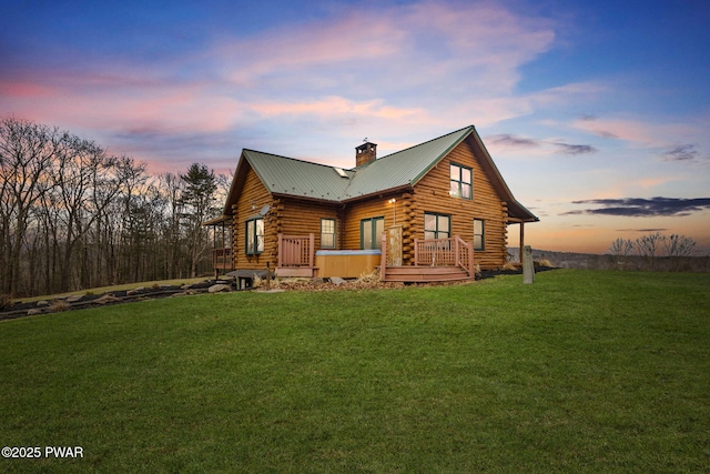 back house at dusk with a yard and a hot tub