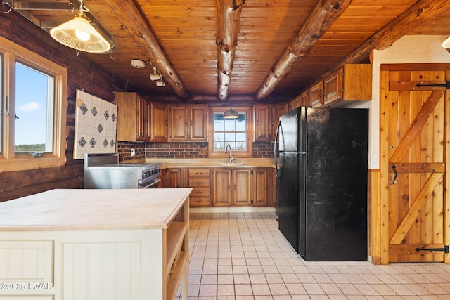 kitchen with beam ceiling, stainless steel electric range oven, sink, a healthy amount of sunlight, and black fridge