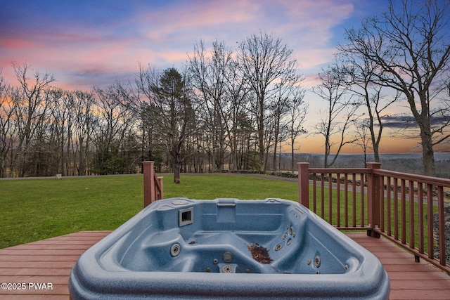 deck at dusk with a yard and a hot tub