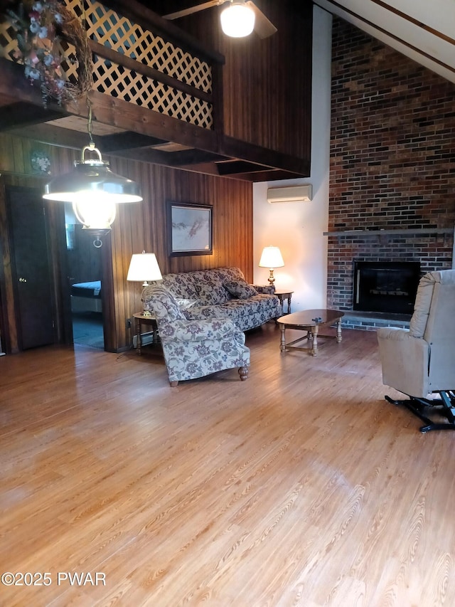 living room featuring wood walls, high vaulted ceiling, light hardwood / wood-style floors, and a brick fireplace