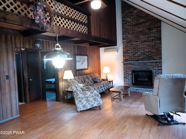 living room featuring hardwood / wood-style floors, wood walls, lofted ceiling, and a brick fireplace