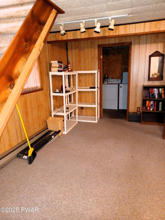 basement featuring washing machine and clothes dryer, wood walls, carpet, and rail lighting