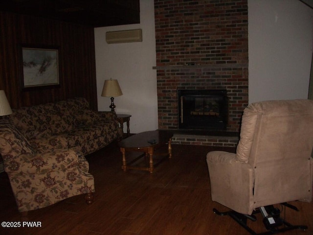 living room with wood-type flooring, an AC wall unit, and a brick fireplace