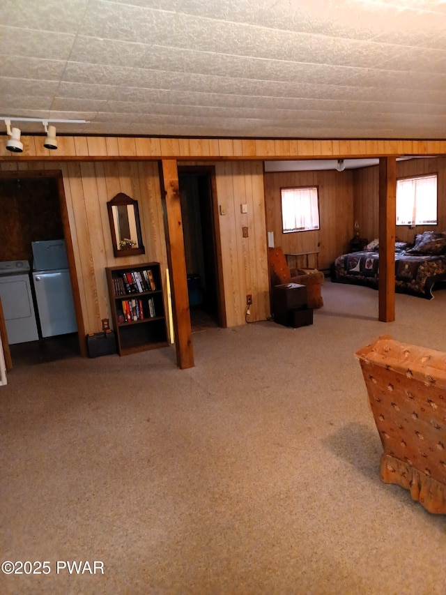 basement featuring carpet flooring, wooden walls, fridge, and independent washer and dryer