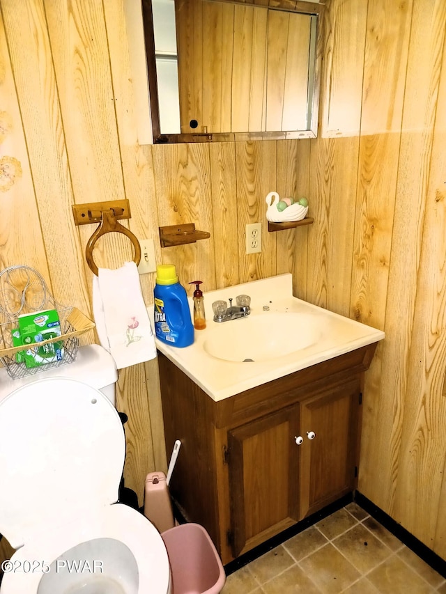 bathroom with wooden walls, vanity, and toilet