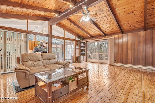 living room featuring vaulted ceiling with beams, wood walls, a baseboard radiator, and light wood-style floors