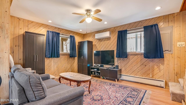 living area with a baseboard radiator, a ceiling fan, and wood walls