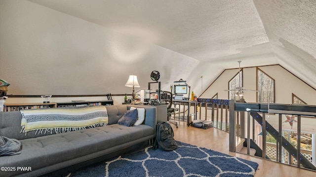 bedroom featuring a textured ceiling, multiple windows, vaulted ceiling, and wood finished floors