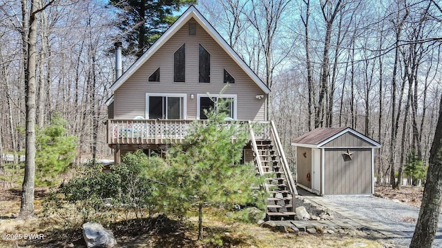 back of house featuring a wooden deck, an outbuilding, stairs, and a shed