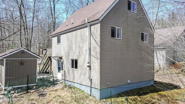 view of side of home featuring a storage unit, an outdoor structure, and a shingled roof