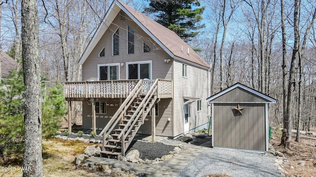 back of property with roof with shingles, a storage unit, a wooden deck, stairway, and an outdoor structure