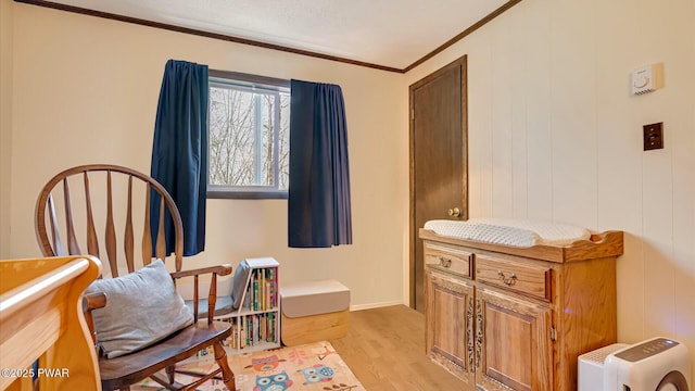 living area featuring baseboards, ornamental molding, and light wood finished floors