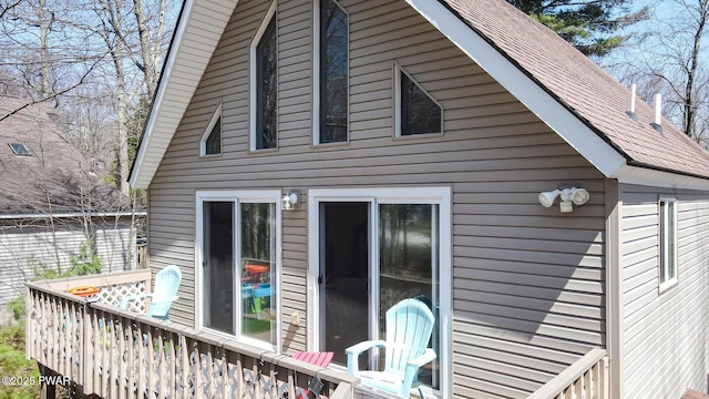 rear view of property featuring roof with shingles and a deck